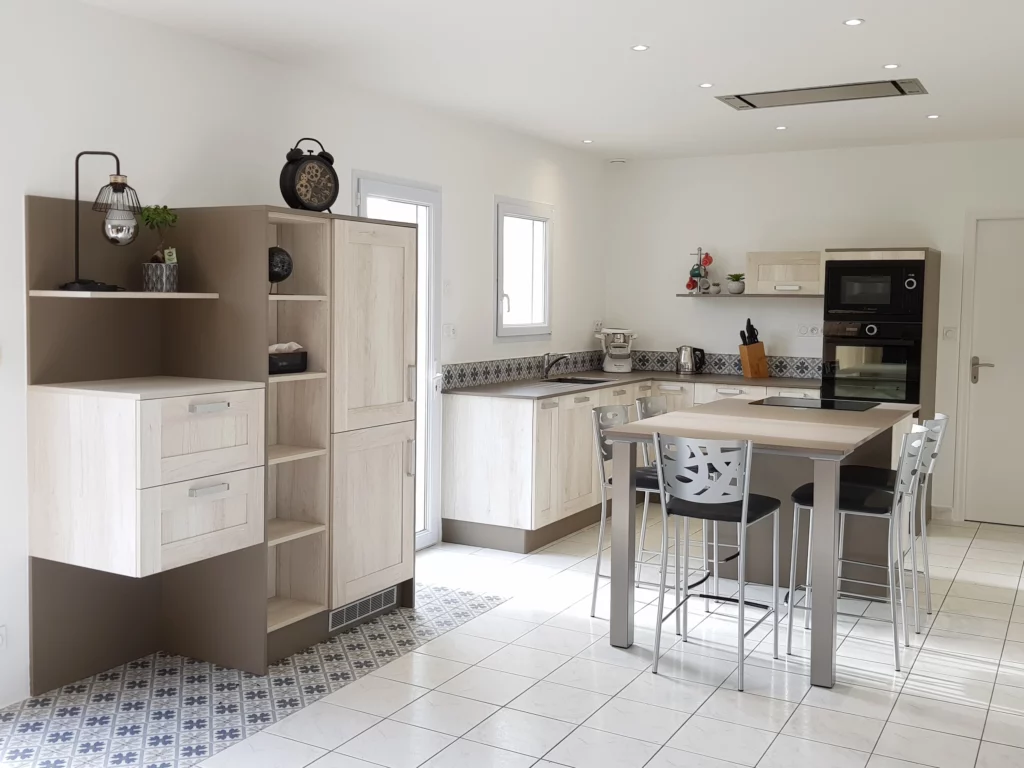 Cuisine moderne composé de trois parties. Îlot central qui sera de table pour déjeuner. Une partie en L avec de nombrexu rangements et un grand plan de travail. Une colonne indépendante pour apporter du rangement à la cuisine.