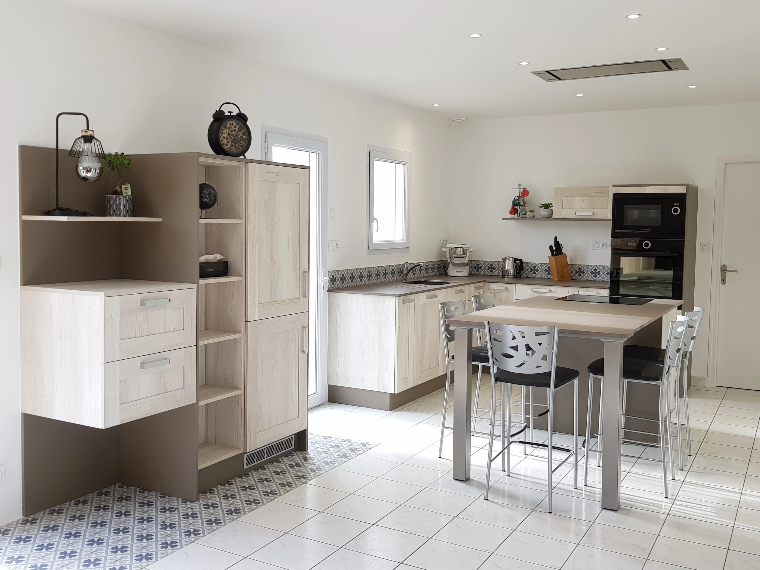 Cuisine moderne composé de trois parties. Îlot central qui sera de table pour déjeuner. Une partie en L avec de nombrexu rangements et un grand plan de travail. Une colonne indépendante pour apporter du rangement à la cuisine.