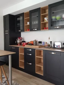 Cuisine moderne sur mesure avec meubles noirs mats et niches en bois.