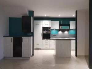 Grande cuisine avec de très nombreux rangements. Façades de placard imitation rainure de bois blanc