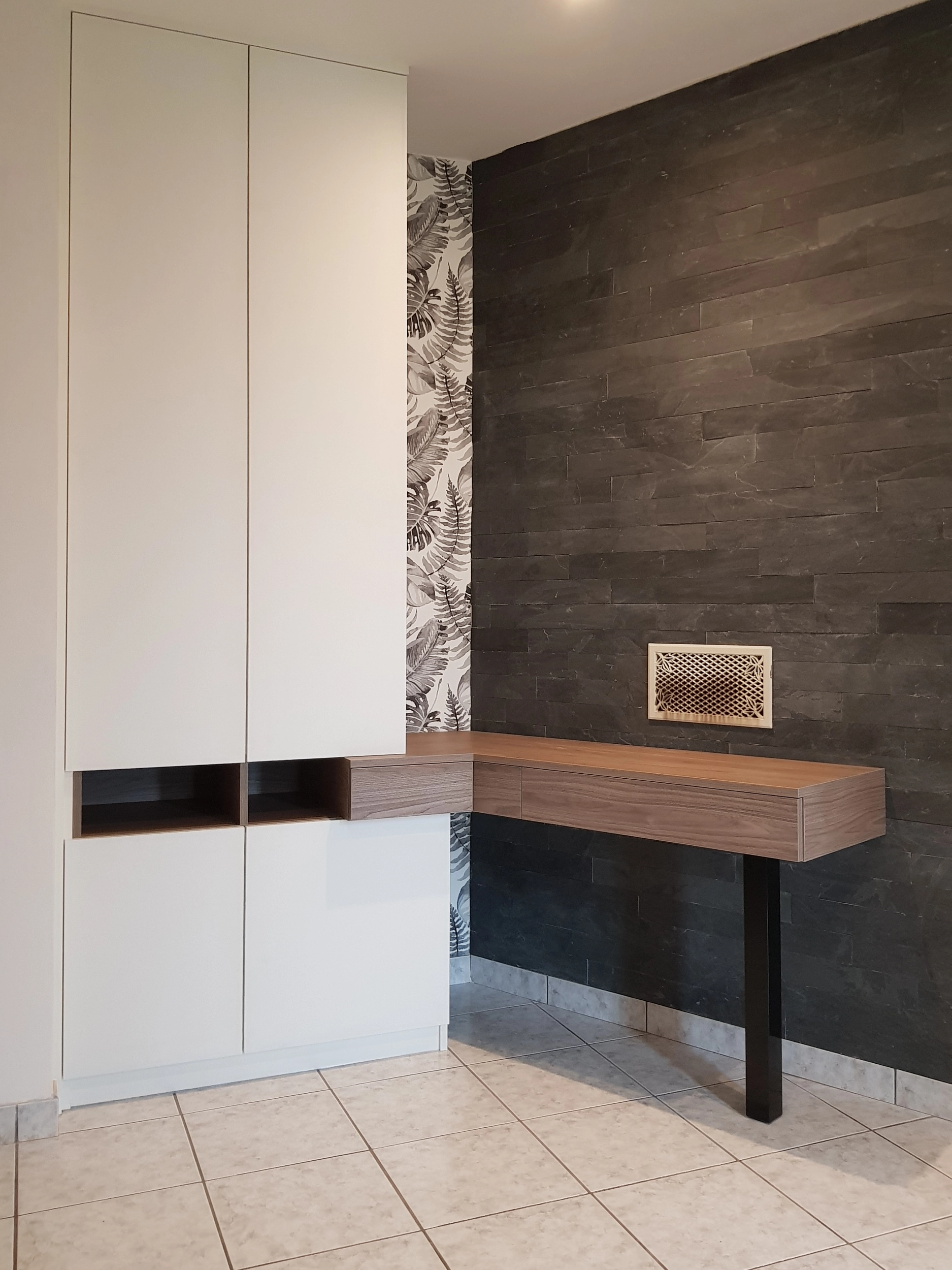 Espace de travail avec un bureau suspendu en bois sans pieds, adossé à un grand placard blanc minimaliste et un mur en plaquettes de parement en ardoise noire.