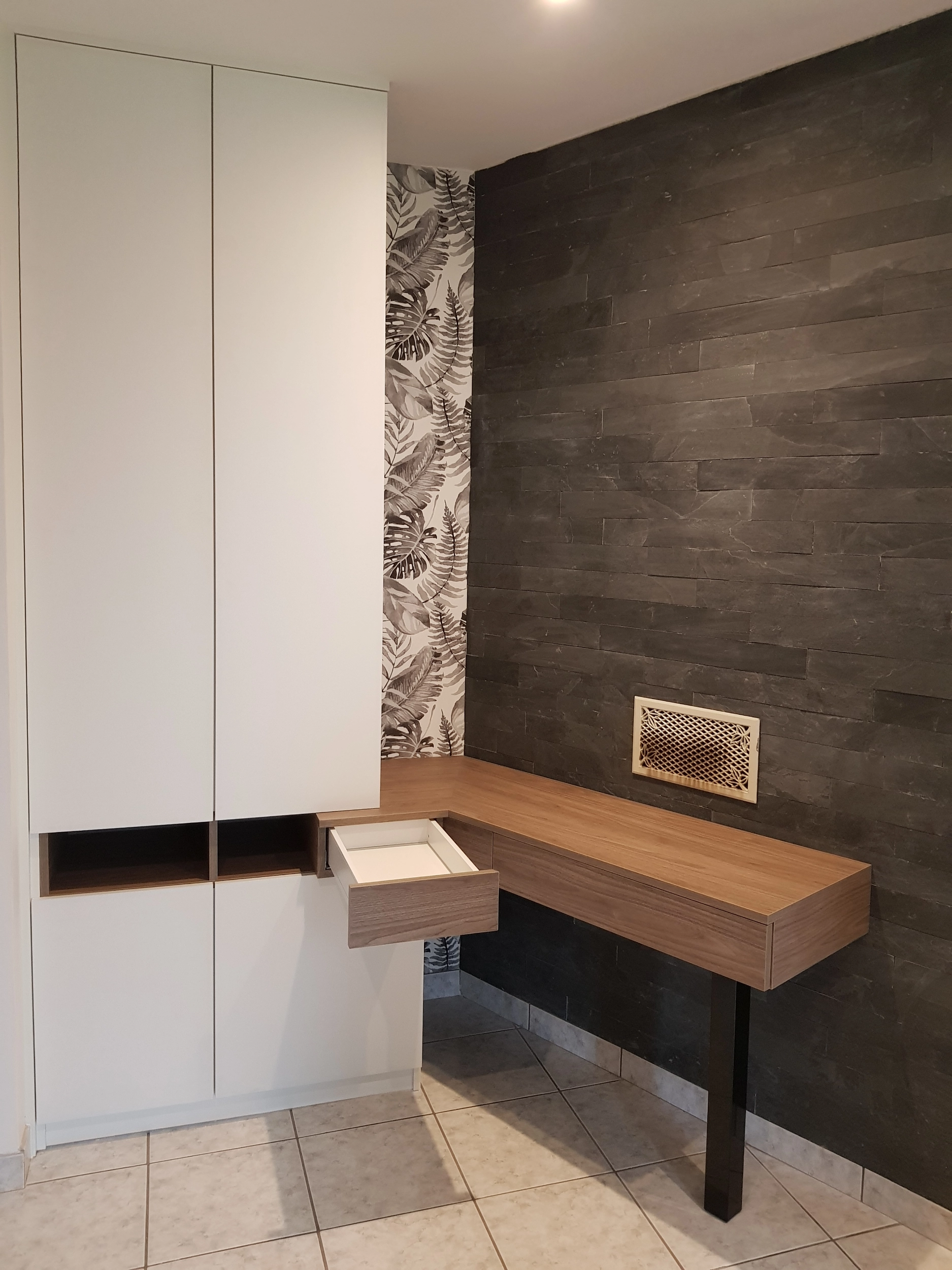 Gros plan sur le tiroir en bois ouvert d'un bureau suspendu sur mesure, révélant son espace de rangement intérieur.