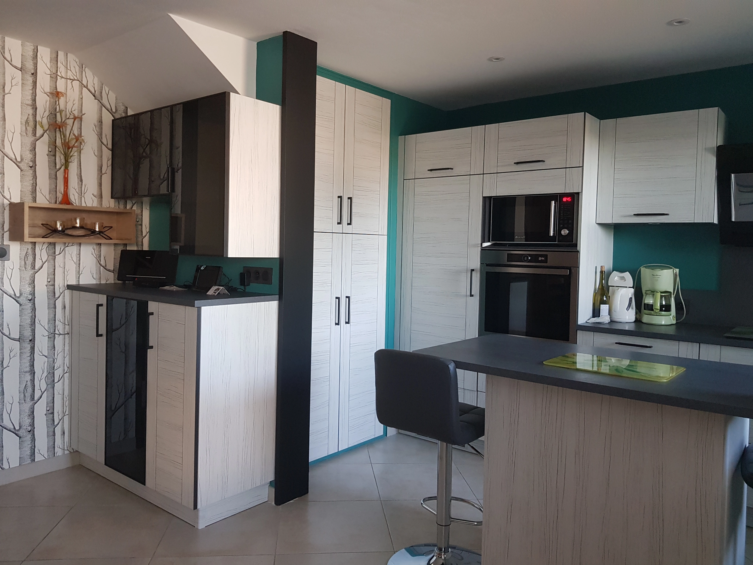 Grande cuisine avec de très nombreux rangements. Façades de placard imitation rainure de bois blanc