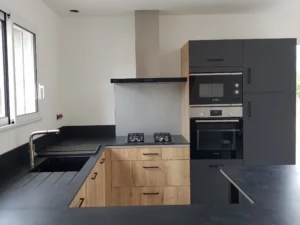 Cuisine moderne de couleur noir pour le plan de travail et certaines façades de placard. Un mélange de façade bois pour contraster et donner le côté moderne de cette cuisine