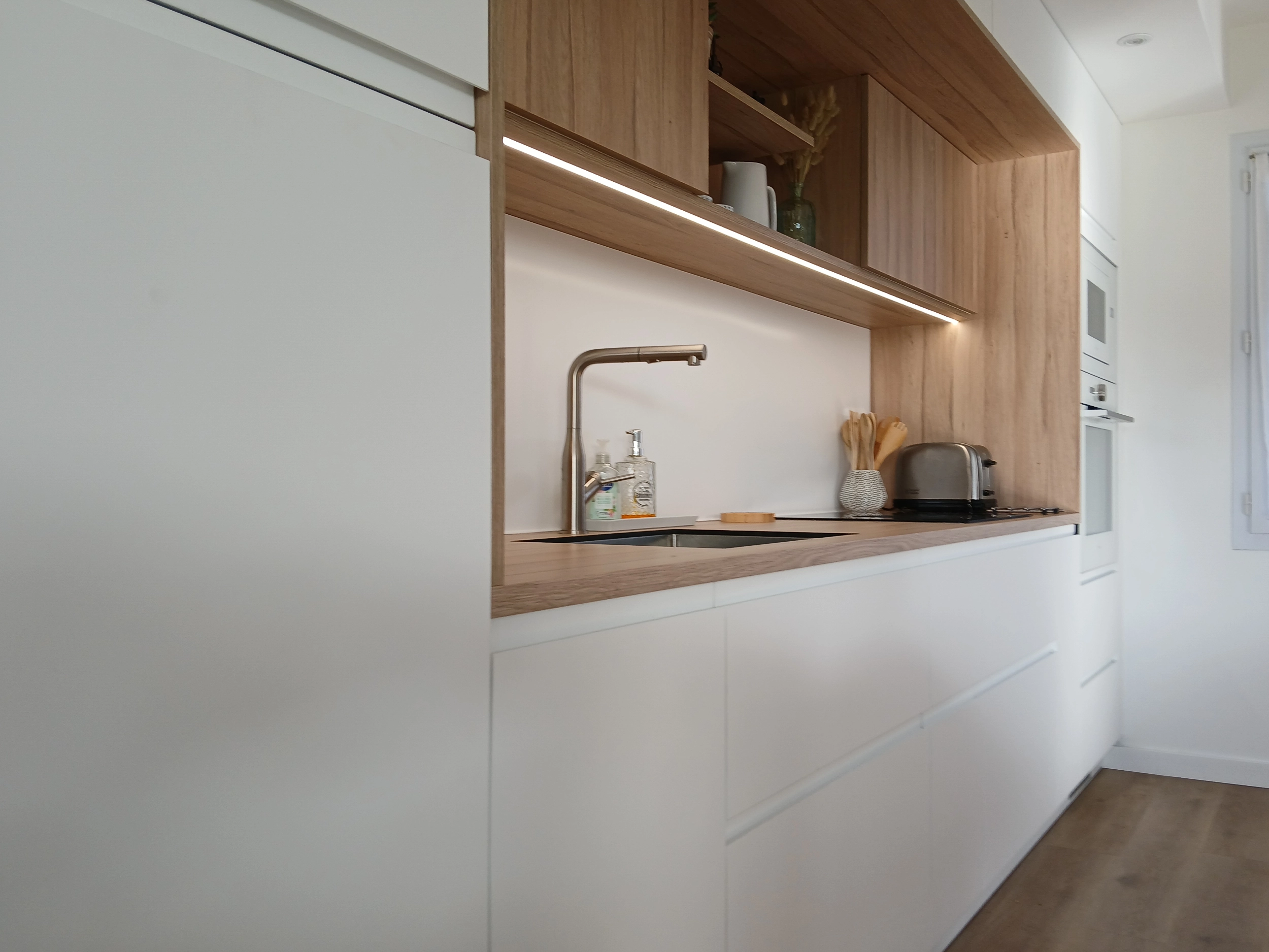 Zoom sur une partie de la cuisine contenant l'espace pour l'évier, la plaque de cuisson, et des rangements de haut en bas.