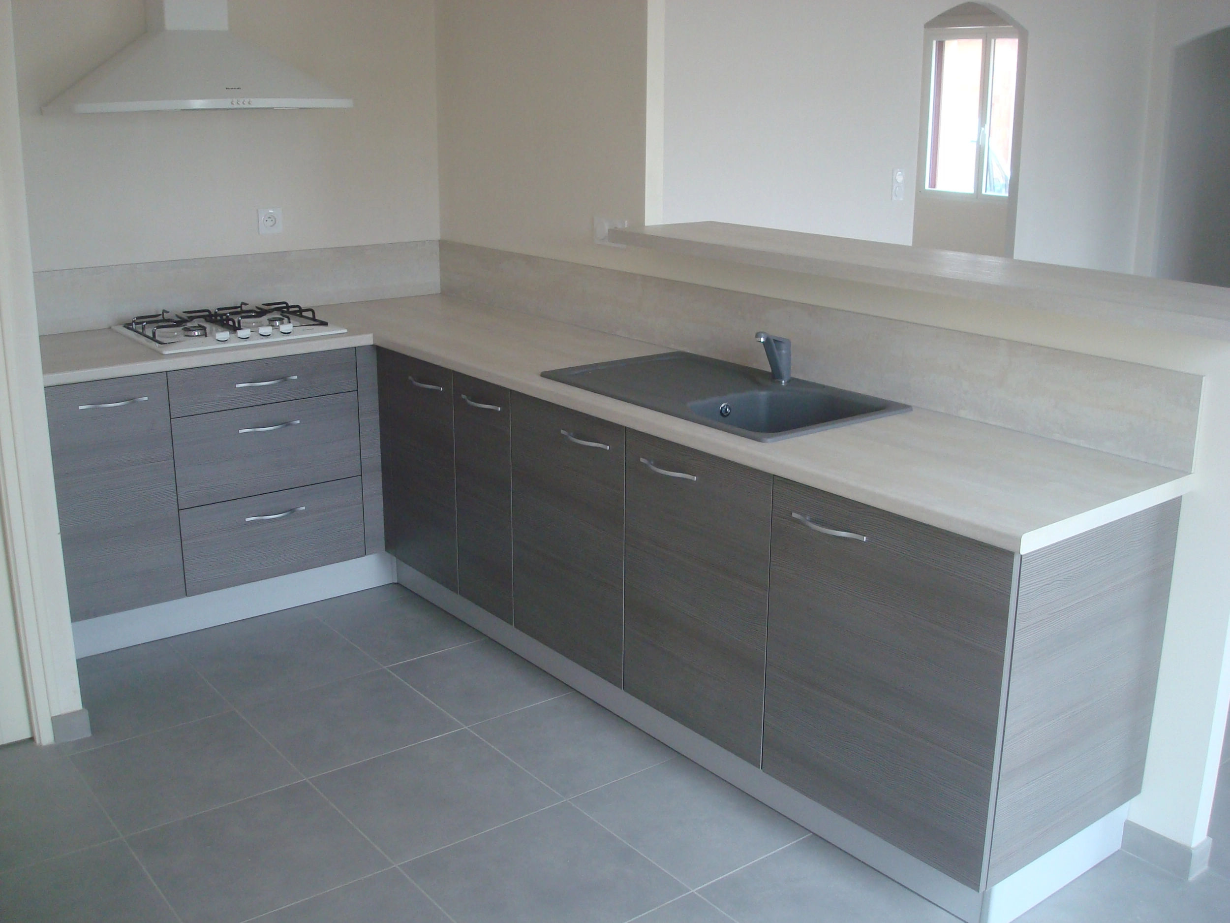 Petite cuisine maison neuve. Plan de travail de couleur gris clair, avec des façades de placards gris foncé.