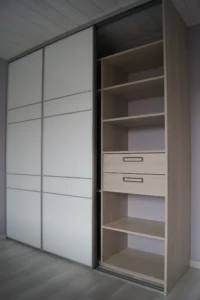 Dressing placard pour une chambre. Il est composé de trois parties chacun accessible grâce aux portes coulissantes blanches.