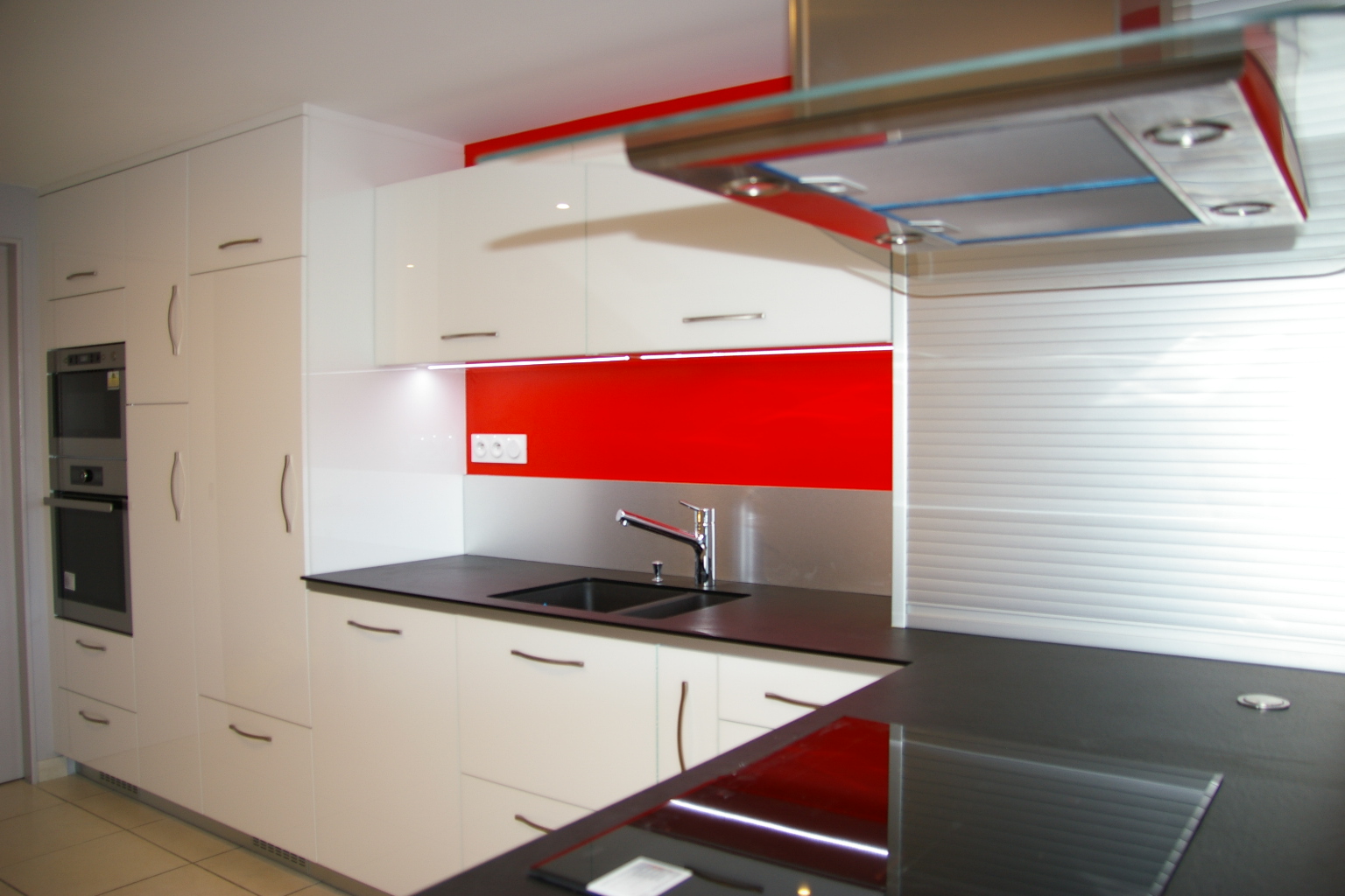 Conception de cuisine laquée blanche sur mesure avec crédence rouge en Vendée.