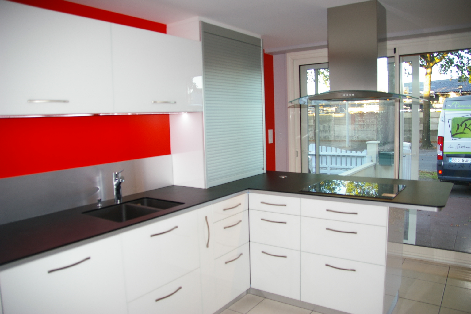 Aménagement de cuisine moderne en L avec îlot de cuisson et meuble à rideau en Vendée.